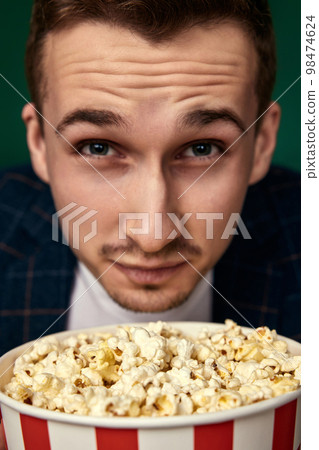 Young caucasian man in 3d glasses eating popcorn 98474624