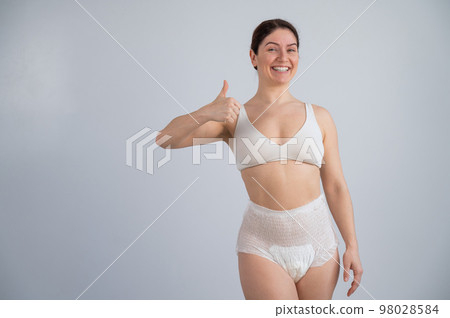 Woman in adult diapers smiling and showing thumbs up. Urinary incontinence problem.  98028584