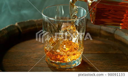 Close-up of pouring whiskey or rum on old wooden barrel 98091133