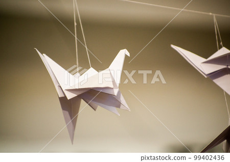 Japanese folded Origami cranes hanging on with strings. Hundreds handmade paper birds isolated with copy space. 1000 thousand crane sculpture topic. Symbol of peace, faith, health, wishes, hope 99402436