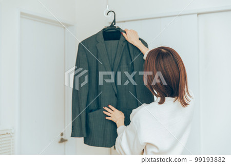 A woman who puts a suit on a hanger housewife 99193882