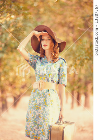 Redhead girl with suitcase at tree's alley. 13887367