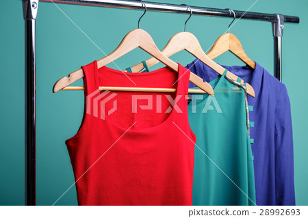 colorful women's shirts on wood hangers on blue 28992693