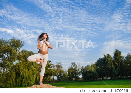 Yoga tree pose by pregnat woman 34670016