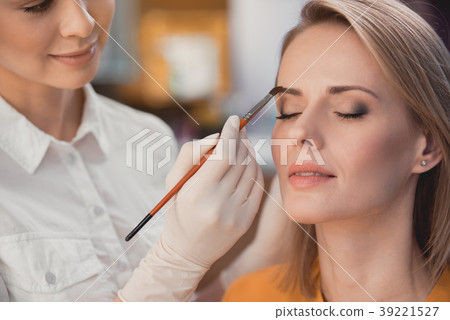 Smiling visagiste painting brows of glad woman 39221527