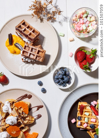 Sweet waffles with berries, cream and fruits on the table. Hard light. Top view on a white wooden background. 101507059