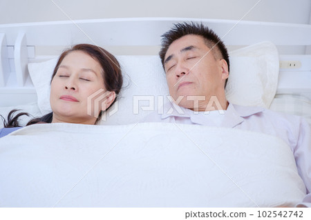 senior couple sleeping in bed 102542742