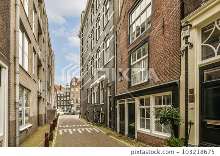 an empty street in the middle of a city with buildings on both sides, and a red bricked building to the other side 103218675