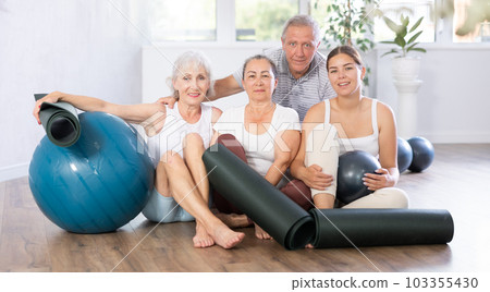 Happy portrait of group of four people with mats and soft balls going to do yoga in gym 103355430