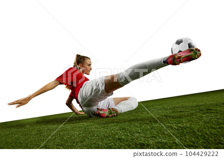 Motivated female athlete, young girl, football player kicking ball in motion on field grass against white background 104429222