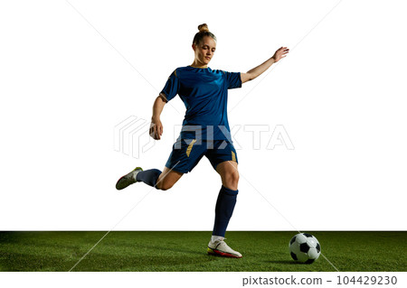 Young sportive girl in blue uniform, football player in motion, training, kicking ball against white background 104429230