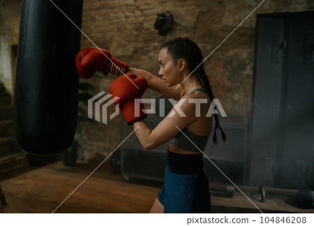 Healthy strong girl fighter boxing with punching bag having workout training 104846208