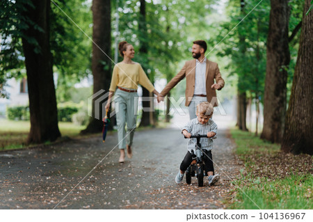 Young family with little son on walk in city park after work. 104136967