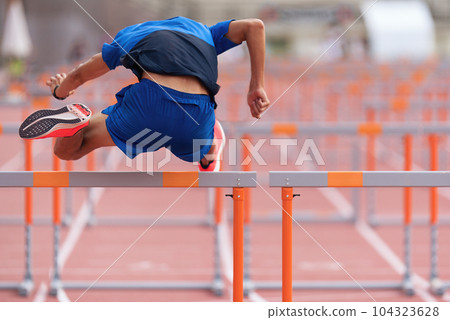 A hurdle runner leaping over the hurdles, man is jumping over the hurdle 104323628