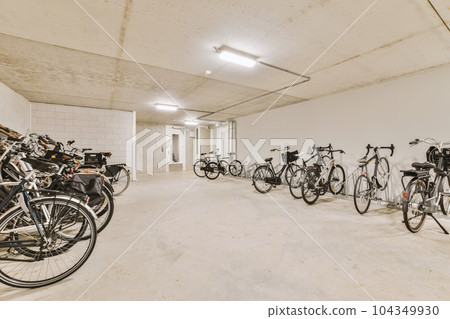 several bikes parked in a room with white walls and concrete flooring on the wall, there is an empty space for them to 104349930