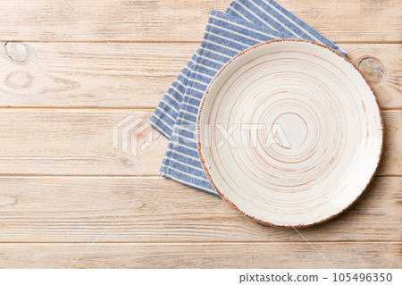 Top view on colored background empty round white plate on tablecloth for food. Empty dish on napkin with space for your design 105496350