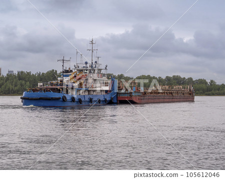 A river towboat pushing an old rusty barge down the river. Towboat and barge connected 105612046