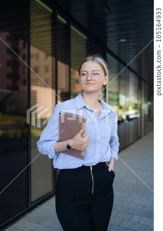 Beautiful elegant professional leader Caucasian woman, female executive retail manager supervisor, small business owner wearing suit holding digital tablet standing outdoor looking at camera, portrait 105164933