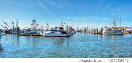 Small fishing trawler and yachts moored at the ocean pier 105258642