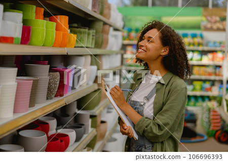 Floral shop owner records the quantity of empty pots on shelf while working in flower store 106696393