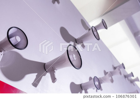 Lots of megaphones on the wall. Conceptual photo of electric horn through which they are trying to convey information. Different loudspeakers in one space. White speakers on white wall 106876301