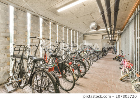 many bikes parked in a room with no one on the floor and two people standing next to each other bicycles 107803720