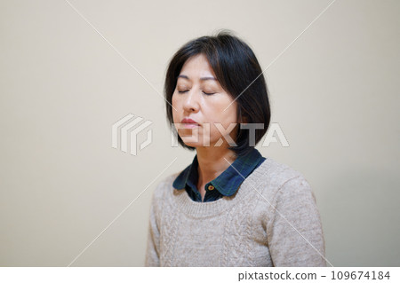 Middle-aged woman wearing a sweater and closing her eyes 109674184