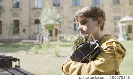 Unhappy school boy sitting alone near school, no friends, bullying problem 109970896