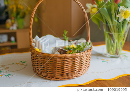 Traditional easter basket with food for blessing. Polish tradition. aster modern eggs, easter bread, ham, beets, butter, in wicker basket decorated with green boxwood branches and flowers on rustic 109019995