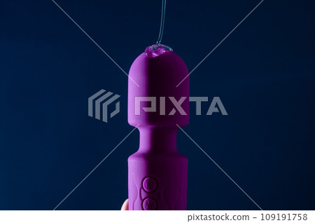 Intimate lubricant pours on a purple vibrator on a blue background. Copy space.  109191758