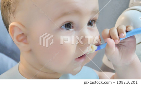 a baby plays with a plastic spoon 109210201