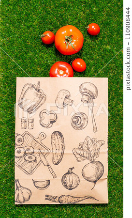 a paper bag lies on the green grass with fruits and vegetables around, moss, mock up 110908444