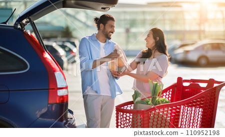 Arab couple loading groceries into car 110952198