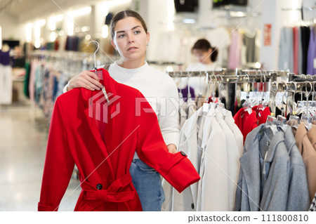 Young woman choosing coat in store 111800810