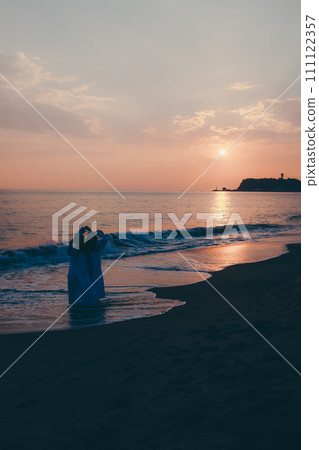 Silhouette of a young woman taking a commemorative photo with the sunset in the background 111122357