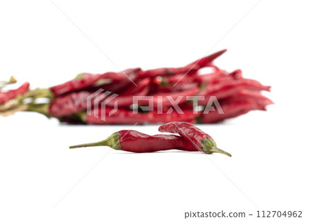 Close-up of red pepper pods on white background and blurred bundle of burning pepper in background. 112704962