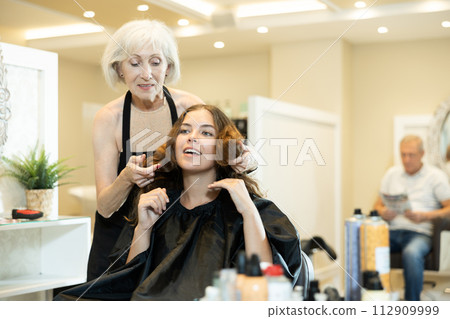 Young girl discussing with experienced female hairstylist while choosing new hairstyle 112909999