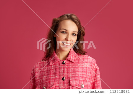 Portrait of beautiful, elegant young woman with nude makeup, curly hair posing with smile against pink studio background 112218981