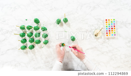 Flat lay. Decorating cactus cake pops with luster dust, sugar glower, and white sprinkles for the Cinco de Mayo celebration. 112294869