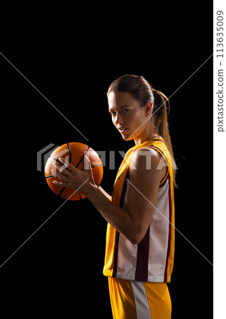 Young Caucasian female basketball player poses confidently in basketball attire, with copy space on 113635009