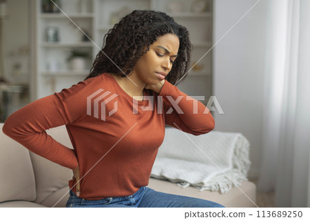 Young Black Woman Experiencing Neck Pain in a Cozy Living Room 113689250