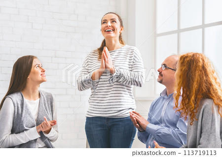 Community members clapping to woman, supporting her at therapy group meeting 113719113