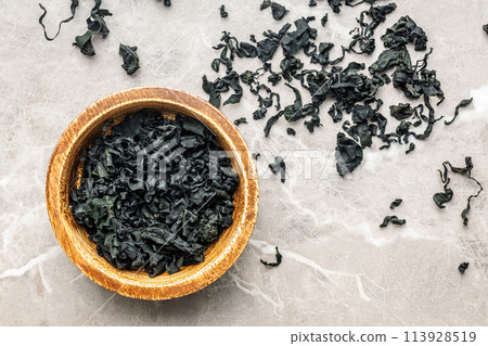 Dried wakame seaweed in bowl on kitchen table. Top view. 113928519