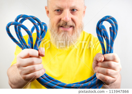 strong colored rope for climbing equipment in the hand of a bearded man in a yellow 113947866