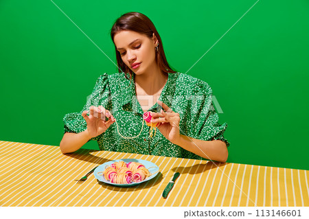 Young woman spinning spaghetti on hair curlers against green background. Unusual presentation of food 113146601