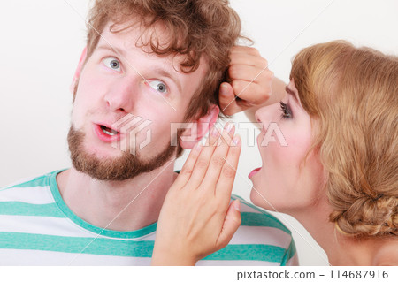 Woman telling an astonished man some secrets 114687916