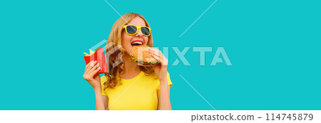 Portrait of happy cheerful young woman eating burger fast food and french fries 114745879