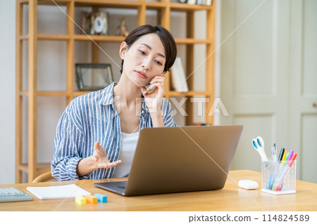 A middle-aged woman who teleworks in the living room. 114824589