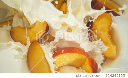 Fresh nectarines pieces falling into cream, top down view 114849135