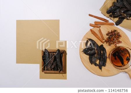 Rustic style photography with many ingredients from nature such as locust, star anise, dried rose buds and cinnamon. Blank vintage brown paper for text or displaying product, view from above 114148756